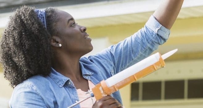 Woman on ladder outside house doing repairs