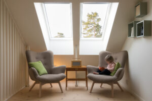 Child sitting in a chair with two skylights in a house