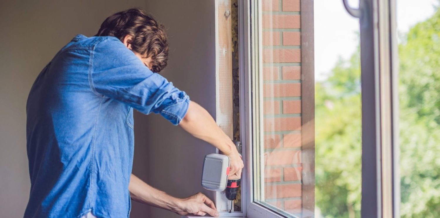 Man in a blue shirt does window installation