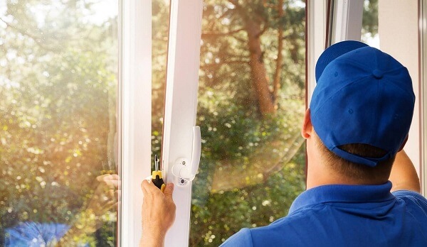 worker in blue uniform installing new plastic pvc window