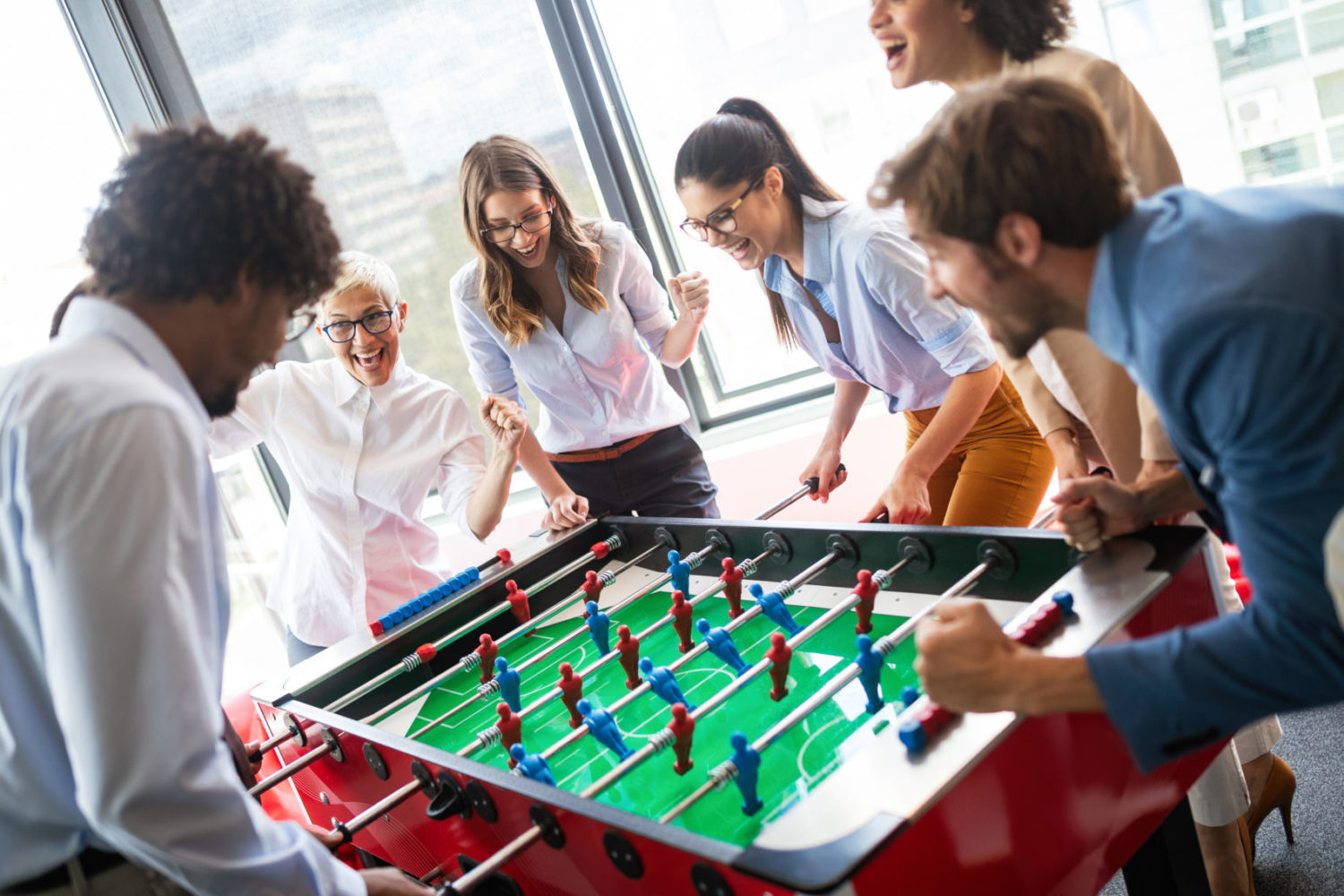 Coworkers gather around a foosball table for a fun game at Window Nation Headquarters