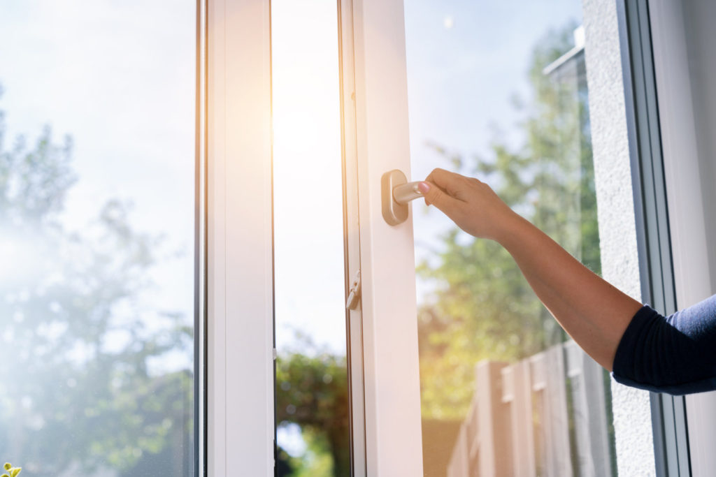 woman opens a window with a mosquito net