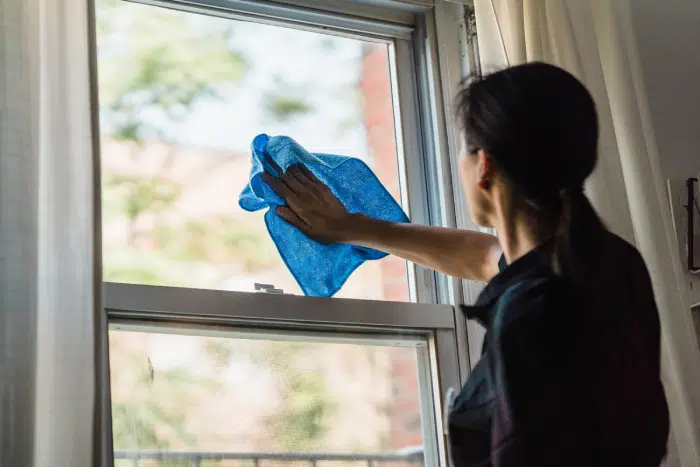 woman cleaning window with a blue rag