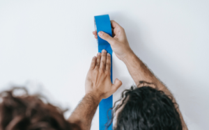 man and woman applying painter tape to a wall