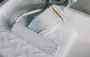 paint brush and roller covered in white paint