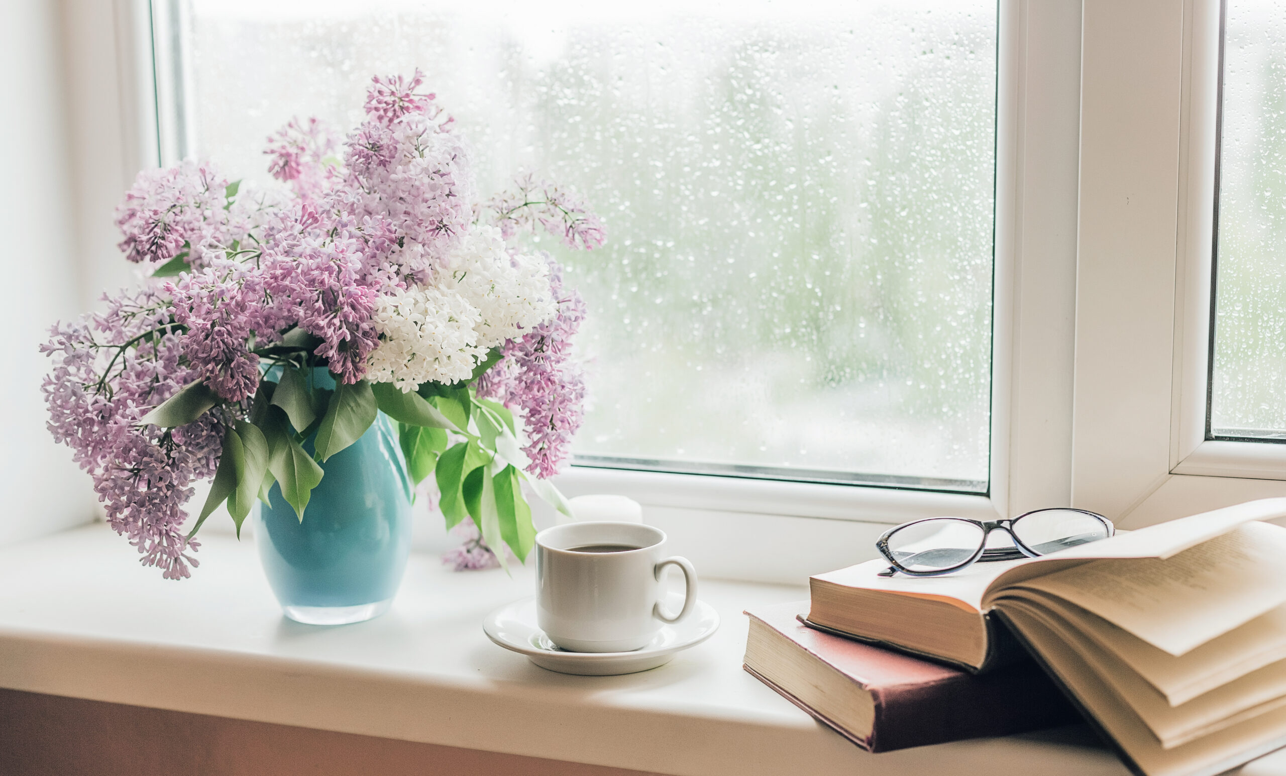 Bouquet of lilacs in a vase,cup of coffee and books on the windowsill