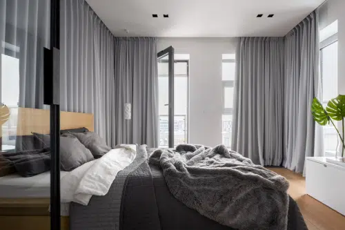 bedroom with bed in the middle, large windows, and curtains