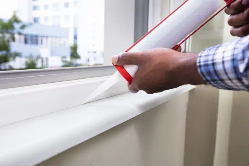 person caulking their window