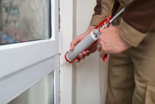 man caulking a window