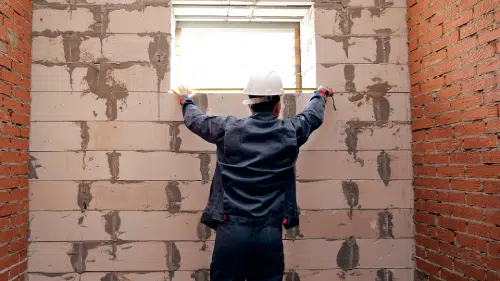 man measuring a specialty window in a basement