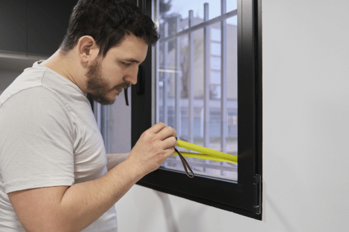 man measuring window depth with a tape measure