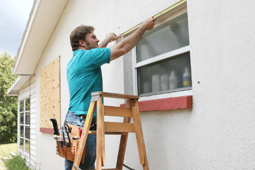 man measuring a window outside