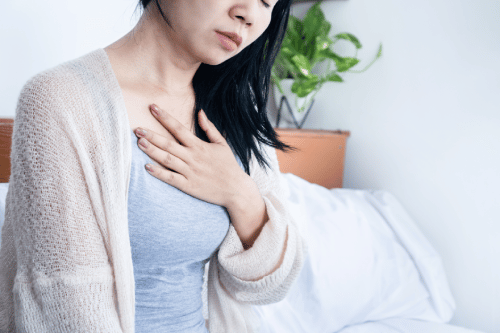 woman holds her chest because of shortness of breath