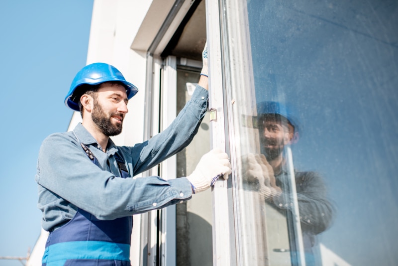 Man in hard hat installs window into a white house