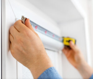 man measuring casing on a window in a house