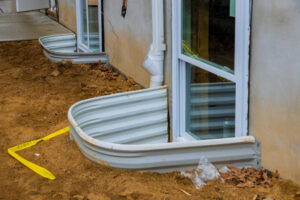 View of a new residential home being built with window wells for the basement